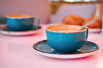 Cup of Cappuccino with Art Milk Foam Top View. Latte with Steel Spoon. Hot Coffee in a Blue Ceramic...