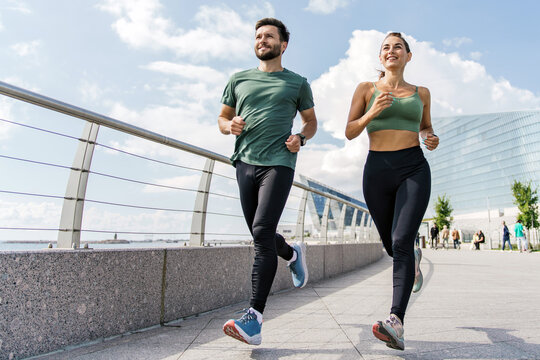 Active couple running together in the city, embodying teamwork and the joy of shared fitness pursuits.