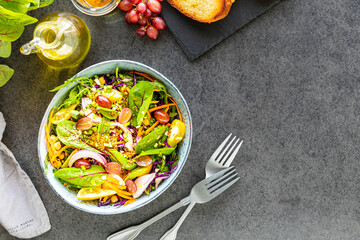 Fresh vegetable and fruit salad in a plate on a black stone background. Top view
