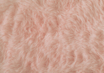 Pinkish orange or peachy pink faux fur background. Close up surface wool texture. Minimal background concept. Trendy color luxury layout. Fluffy fur flat lay. Retro fashion aesthetic idea. Copy space.