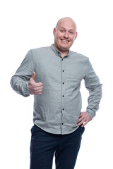 Smiling bald man. A guy in a gray shirt and blue trousers stands and shows like with his hands. Positive and optimistic. Isolated on a white background. Vertical.