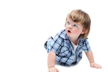 A little boy on all fours looks up in surprise. A child with a fashionable haircut wearing a blue checkered shirt and jeans. Curiosity and spontaneity. Isolated on a white background. Space for text.
