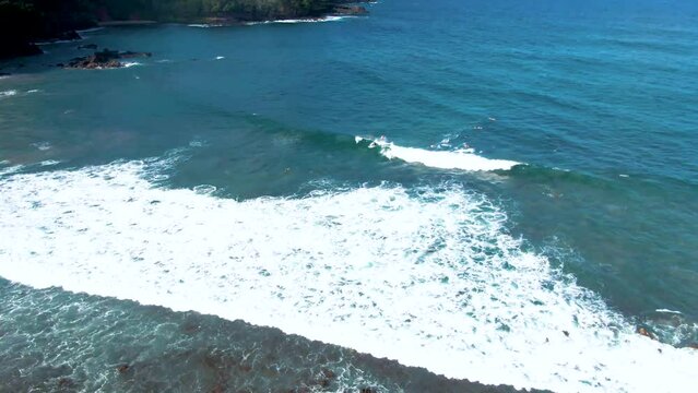 Aerial orbiting shot of Surfer ride a wave in the Koki Beach in Maui Coastline