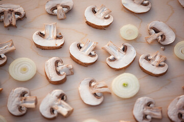 Sliced champignon mushrooms and sliced onion on wooden table, top view. Mushroom background for...