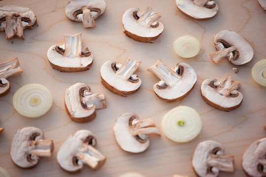 Sliced champignon mushrooms and sliced onion on wooden table, top view. Mushroom background for publication, poster, calendar, post, screensaver, wallpaper, cover. High quality photo