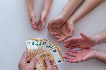 Old grandfather or grandmother hands giving 50 euros banknotes to another pairs of hands of his her...