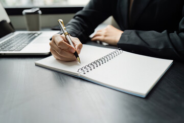 Business woman working in office writing plan on note book and use computer laptop meeting online