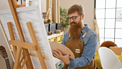 Confident young redhead man rocking the art studio, smiling as he lets his creativity run wild,...