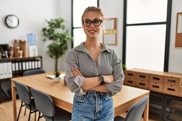 Young caucasian woman business worker smiling confident standing with arms crossed gesture at office