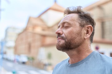 Middle age man breathing with closed eyes at street
