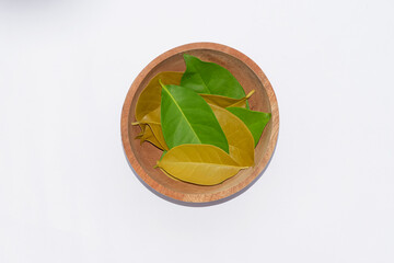 Obraz premium Bay leaves in a wooden bowl isolated on white
