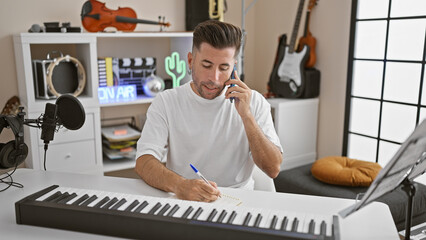 Young hispanic male muso, pianist, in his element, writing notes in a notebook, engaged in a...