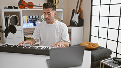 Handsome, young hispanic man intensely focused, online piano lesson swirls melody through music...