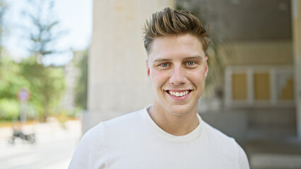 Confident young caucasian man, sporting casual look, caught smiling standing on a bustling street...