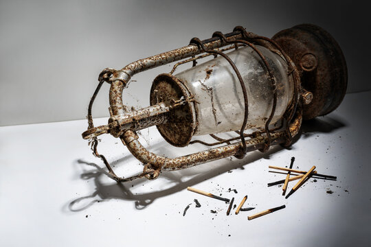 Old rusty kerosene lamp and burnt matches lying on a gray background, symbolizing outdated concepts that are no longer in keeping with the times, copy space