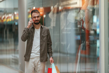 Talking by phone. Man is shopping in the supermarket