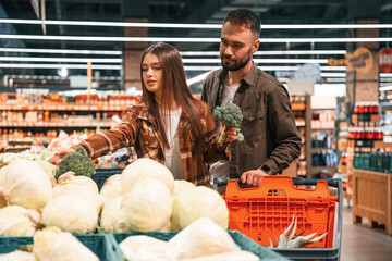 Fresh vegetables. Young couple are in supermarket together