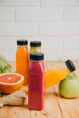 Fruit and vegetable smoothies in transparent plastic bottles. Red, green, orange smoothies on a wooden table with women's hand. The concept of healthy eating. Front view