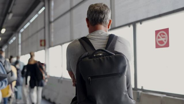 This video captures a man wearing a backpack as he walks through an airport, providing a glimpse into the bustling atmosphere and travel experience.