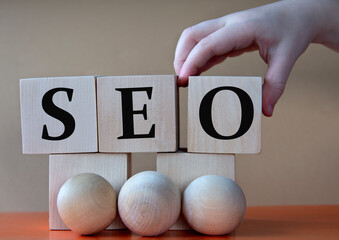 A child's hand places a large cube next to other cubes. SEO acronym concept