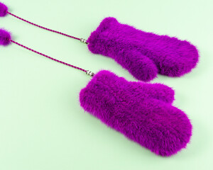 Luxury pink fur mittens on green background. Minimal fashion concept.