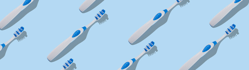 A large group of toothbrushes forming a repeating pattern on a blue background. Top view. Web...