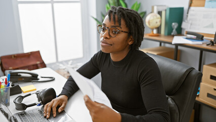 A professional african american woman with dreadlocks working in a modern office.