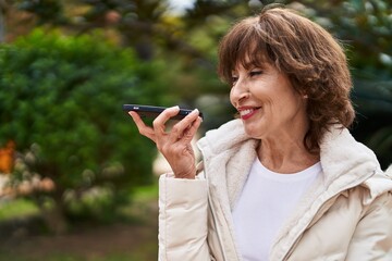 Middle age woman smiling confident talking on the smartphone at park