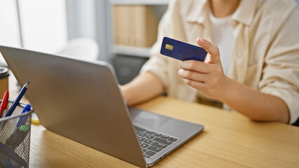 Empowered hispanic woman business worker, deftly handling credit card and laptop at her luxurious office.