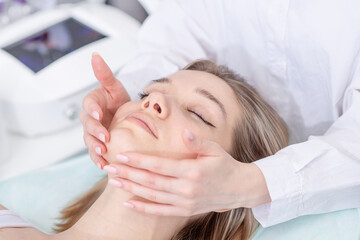 Fototapeta na wymiar Pretty young woman having face massage in spa. Facial treatment at beauty salon