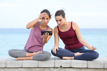 Fototapeta na wymiar Amazed yogis watching yoga tutorial on phone