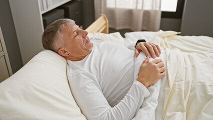 Obraz premium Middle-aged man relaxing in a cozy bedroom, conveying a sense of tranquility and comfort.