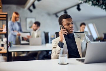A black businessman making a phone call while working in the co-working space.