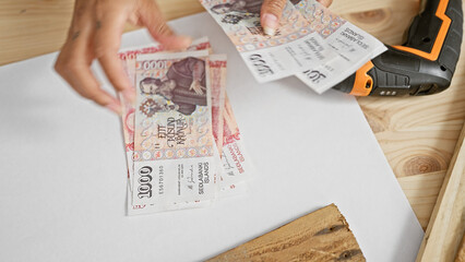 Obraz premium A person handles icelandic krona on a workbench, hinting at a transaction or financial topic in a work setting.