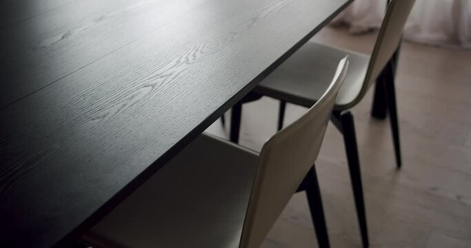 A dark room with hardwood flooring sets the stage for a dining room table and chairs, creating an elegant and intimate setting for any event