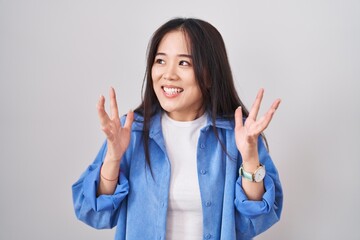 Young chinese woman standing over white background celebrating mad and crazy for success with arms...
