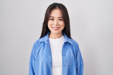 Young chinese woman standing over white background with a happy and cool smile on face. lucky...