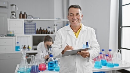 Together in science, man and woman scientists engrossed in medical research, writing on clipboard,...