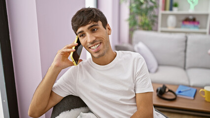 Handsome young hispanic man, oozing confidence, smiling joyfully while engrossed in a phone...