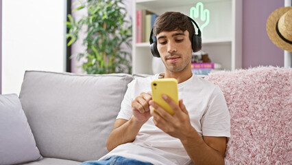 Relaxed young hispanic man, a portrait of serenity, effortlessly listening to his favorite song on...