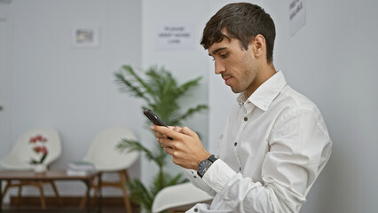 Serious young hispanic man, a successful professional, sitting relaxed in a chair, engrossed in...