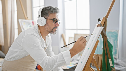 At the studio, a relaxed, young hispanic man with grey-haired beard, artist and student, drawn to...