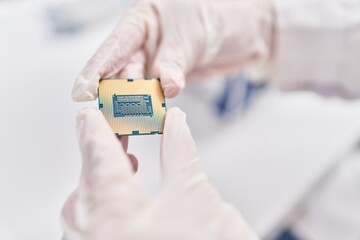 Young blonde woman scientist holding cpu processor chip at laboratory