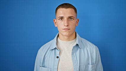 Handsome young hispanic man in casual clothing posing against a blue isolated background outdoors.