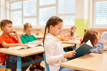 Girl reading book sitting in classroom