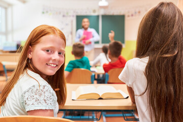 Smiling girl sitting with classmate in school