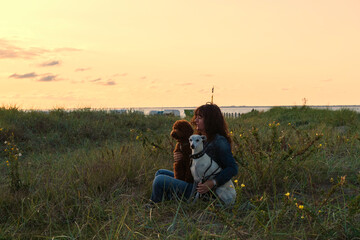 Fototapeta na wymiar Frau mit ihren Hunden bei Sonnenuntergang in den Dünen