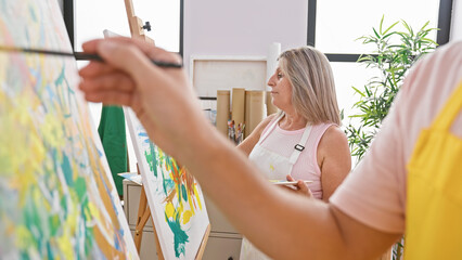Two artists, a man and woman, delving deeply into their art! drawing together in a cozy studio,...