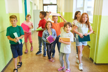 Elementary kids holding books in hallway at school