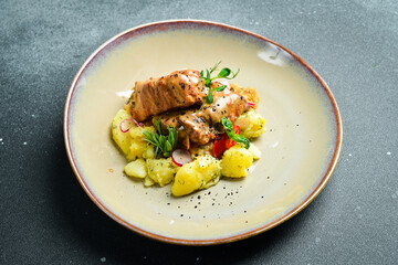 Stewed pork ribs in a cream sauce, with boiled potatoes. On a plate. Restaurant serving. Close up. On a dark stone background.